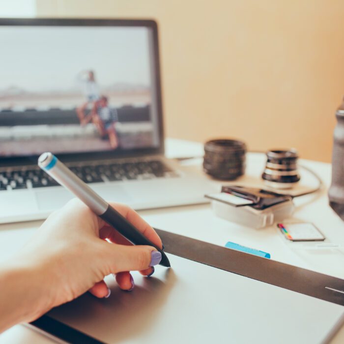 Graphic Designer working with interactive pen display, digital Drawing tablet and Pen on a computer. Smooth tracking shot with nice backlit lensflare.On a background photo camera and laptop