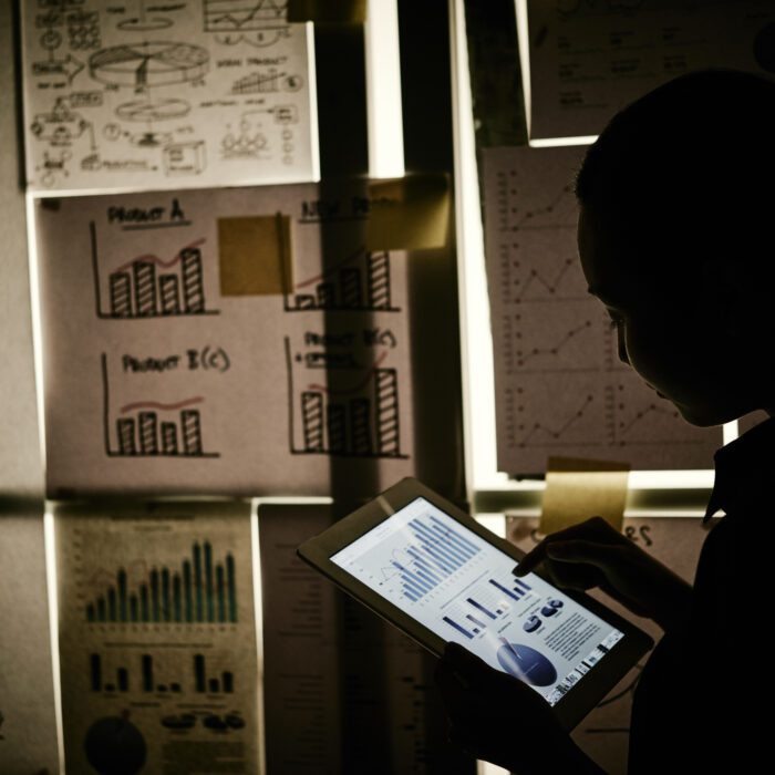 Working in darkness Business lady analyzing chart on tablet computer in dark office